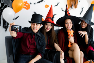 Group young Asian in costume witch, wizard celebrate party and selfie in the room.