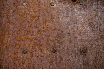 Rusted red metal surface with studs - background or texture