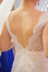 The bride dresses a wedding dress. Dress with an open back. Lace wedding dress. Bride foreshortening from the back.