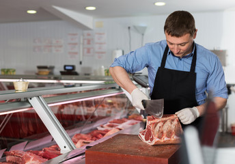 Butcher cutting raw steak on ribs