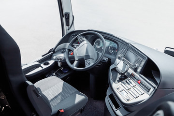 The driver cab of a bus with a steering wheel and various devices and gadgets