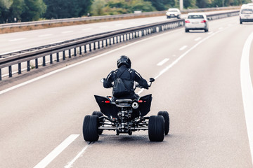 All-terrain vehicle quadbike riding on a highway © EdNurg
