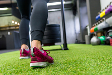 Low angle view of female pushing sled in local gym.