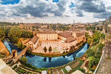 Naklejka premium Panoramic view of the Church of St Jean du Grund and the old town in the valley of the river Alzette. Travel destinations in tiny country of Luxembourg