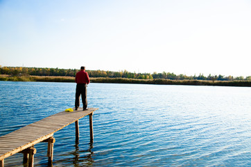 fisherman on a bridge near a blue lake