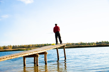 fisherman on a bridge near a blue lake