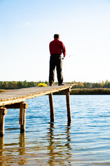 fisherman on a bridge near a blue lake