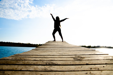 Fototapeta na wymiar girl doing yoga and sports martial arts on a bridge on a lake