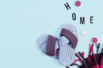 Cozy home concept. Knitted slippers, coffee and letters arranged in a word Home, top view