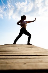 Fototapeta premium girl doing yoga and sports martial arts on a bridge on a lake