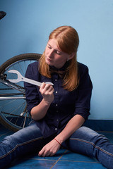 Plakat pretty girl sitting on the floor of a bike shop near a bike