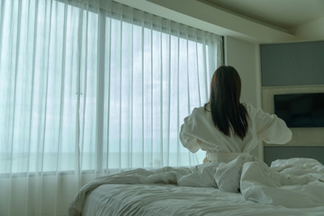 Obraz na płótnie Canvas Behide asian woman in bathrobe suit wake-up on a bed in the hotel, Travel and Holiday concept