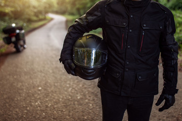 Handsome and attractive man is holding a helmet and wearing raiders clothes, preparing for the ride.