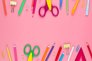 Colorful school supplies over a paper on pink background with place for your text