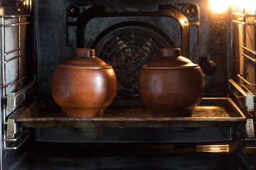 Two clay pots on pan in the oven
