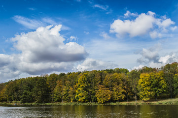 Fototapeta na wymiar Autumn forest river landscape. Blue sky and clouds
