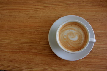 Hot latte in white cup  on wooden table.