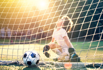 Soccer ball in goal on green grass. Disappointed football team goalkeeper following goals. Goalkeeper emotionally reacts after missed goal during game. Defeat Concept. selective focus