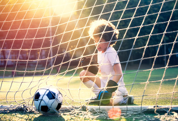 Disappointed football team goalkeeper following goals. Goalkeeper emotionally reacts after missed goal during game. Defeat Concept