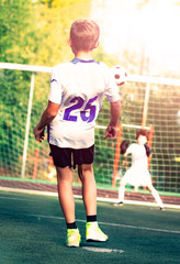 Kids play football on outdoor field. Football pitch. Sports training for player. kid football player prepairing to take a shot on a football field. selective focus