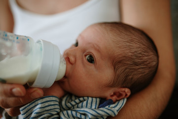Closeup portrait of 1 month old baby eating milk from bottle