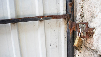 Rusty lock hangs on a damaged gate 