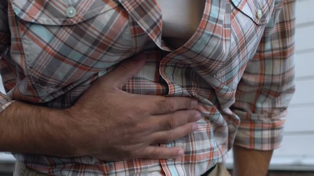 Adult man having indigestion problem, touching stomach, abdominal bloating