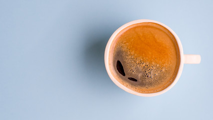 Ceramic cup with black coffee on a bright blue background, top view. Espresso or americano. Cafe and bar, barista art concept.