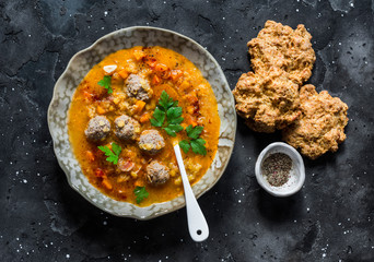 Lentil meatballs thick rich soup and corn flour cheese scones on a dark background, top view....