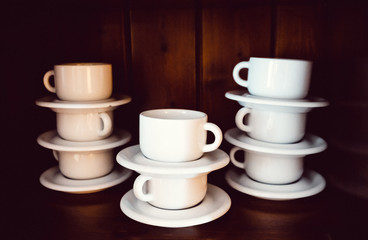Set of white cups in a cupboard, piled