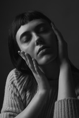 Fototapeta premium Young woman with hands on face. Black and white. Close up