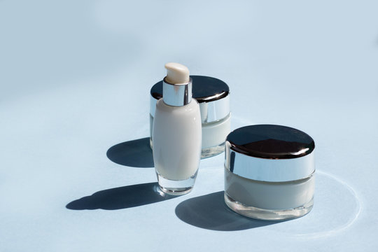 Face cosmetics. Jars of cream, serum and face mask on a blue background with hard shadows. Beauty blogger, procedures salon concept. Minimalism.
