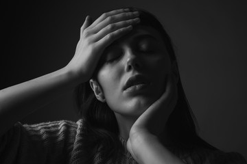 Young woman with hands on face. Black and white. Close up. Sadness, depression or despair