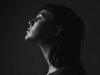 Young woman in profile close up. Black and white. Low key