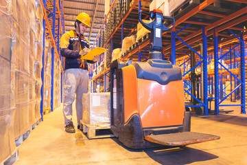 warehouse worker hand holding clipboard inspecting checklist goods pallet with electric forklift pallet jack. © Siwakorn1933