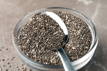 Glass sauce boat with chia and spoon on textured background, close up