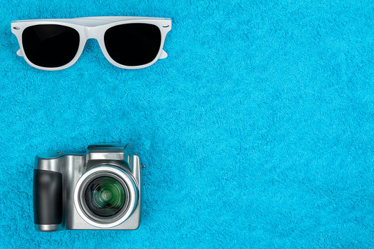 Sunglasses and a camera lie on a towel.