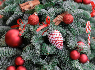 Natural branches of spruce decorated with Christmas toys in the form of red balls and cones, cinnamon sticks, candy canes - winter holidays background.