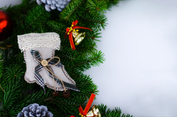 The Christmas wreath is decorated with New Year's toys - a Christmas sock, decorative pine cones, glass red balls, bells.