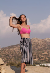 Girl in a pink swimsuit on a hill background