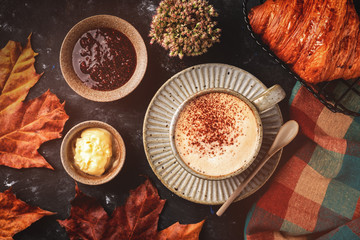 cappuccino coffee with croissant on the table, autumn breakfast concept, top view