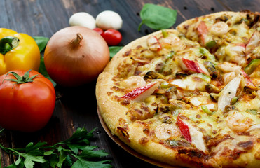 seafood pizza, and ingredients, vegetables to decorate around such as tomato chili mushroom garlic. on the wooden table background.