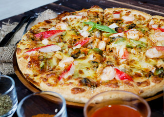 seafood pizza, and ingredients, vegetables to decorate around such as tomato chili mushroom garlic. on the wooden table background.