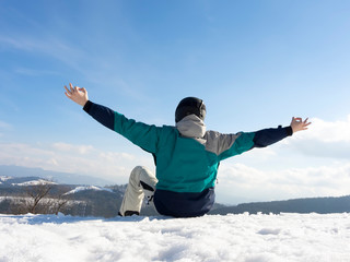 The guy is a snowboarder enjoying a view of the ski resort