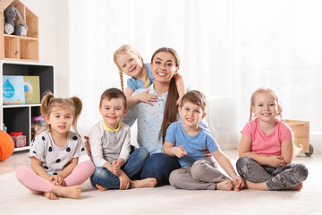 Kindergarten teacher with group of children in playroom. Indoor activity
