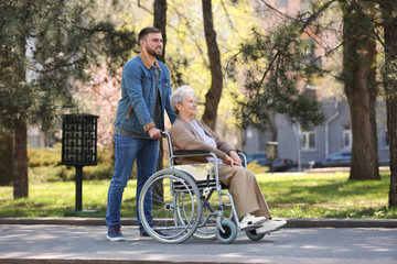 Obraz premium Senior woman in wheelchair with young man at park