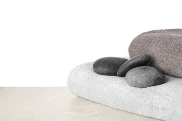 Towels and spa stones on table against white background