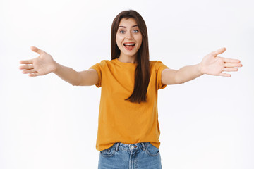 Friendly, carefree outgoing woman see familiar face in crowd, spread hands in greeting, giving warm welcome, cuddle or hugging friend smiling, asking guests come in, standin white background