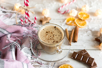 Hot cup of cappuccino or hot milk chocolate with dried orange fruit and cinnamon.