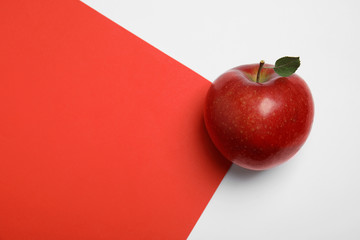 Ripe juicy red apple with leaf on color background, top view. Space for text